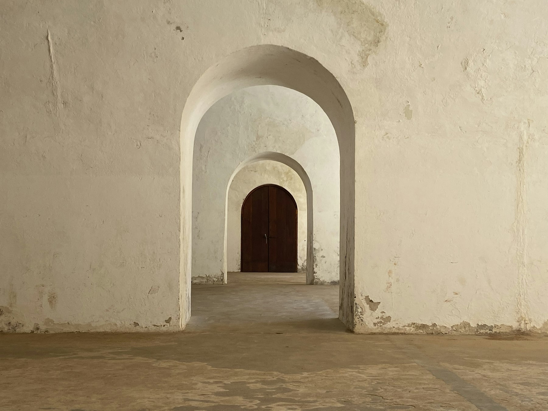 White plastered arches receding to a timber door