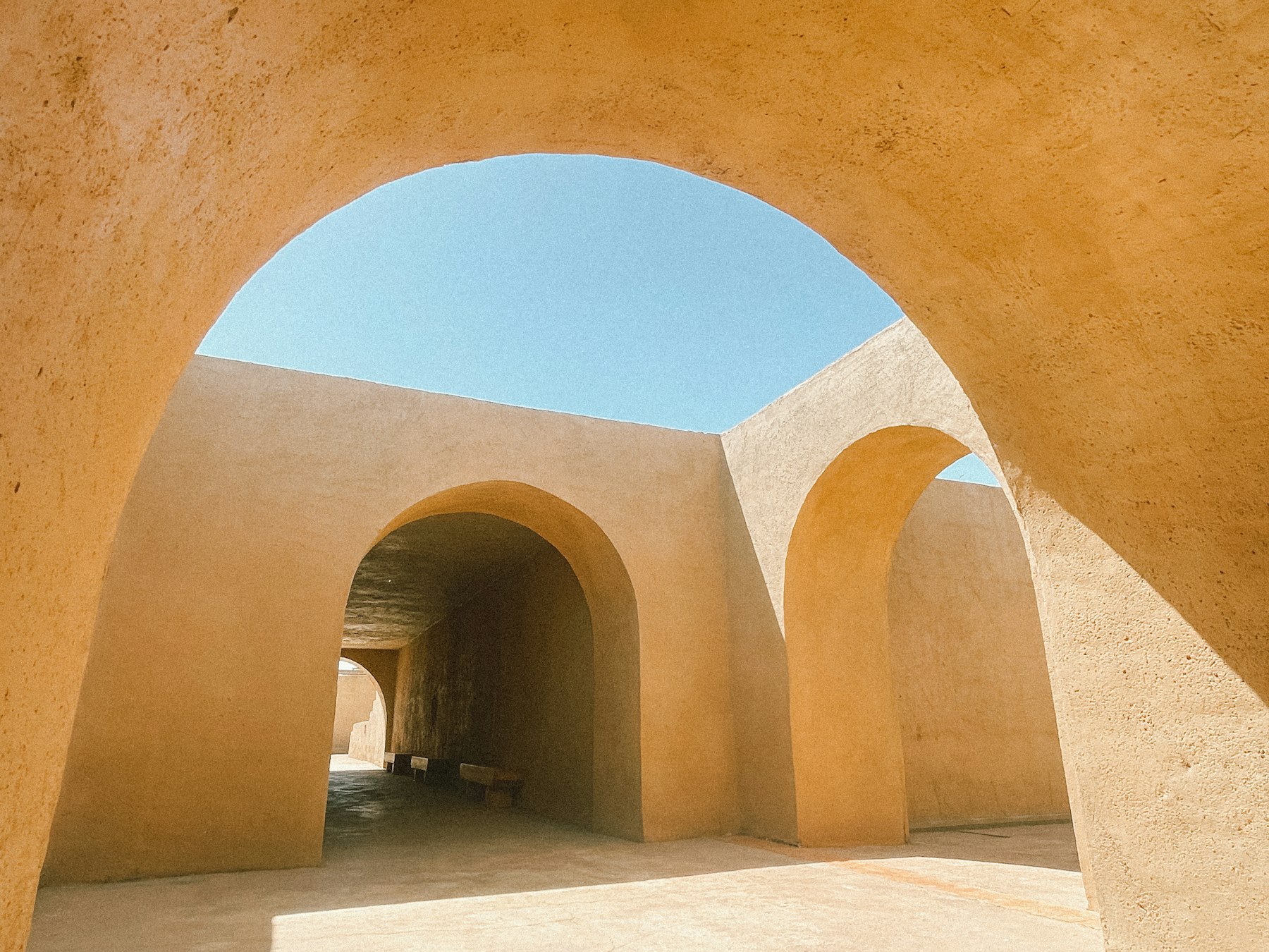 Warm terracotta arches opening onto a pale sky