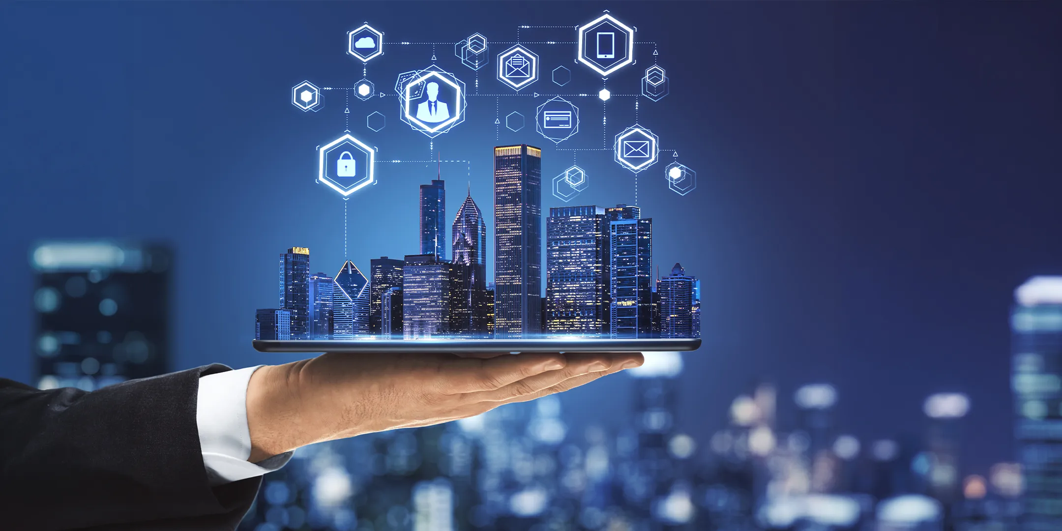 Hand holding a digital tablet projecting a city skyline with technology and security icons connected above it.