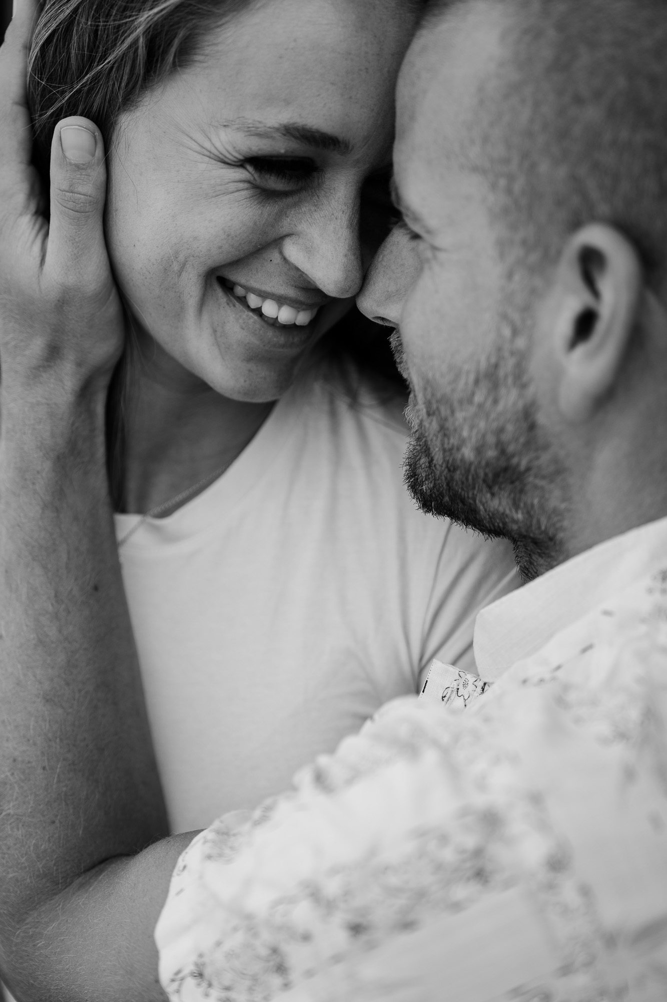 Black-and-white close-up of a smiling couple touching their faces together.
