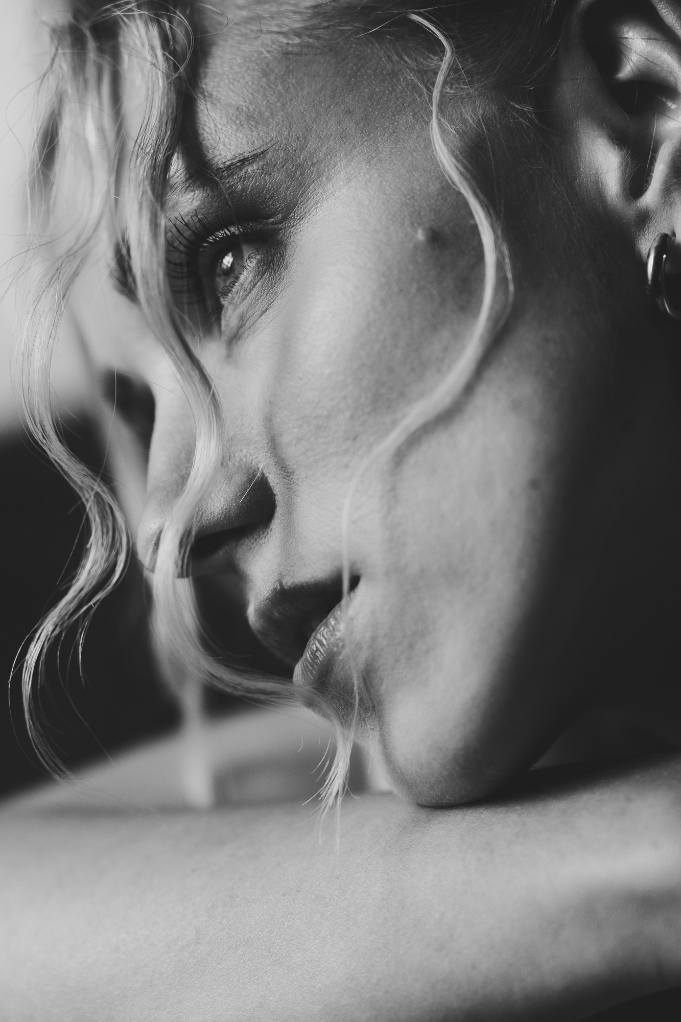 Black-and-white close-up portrait of a woman with loose hair across her face.