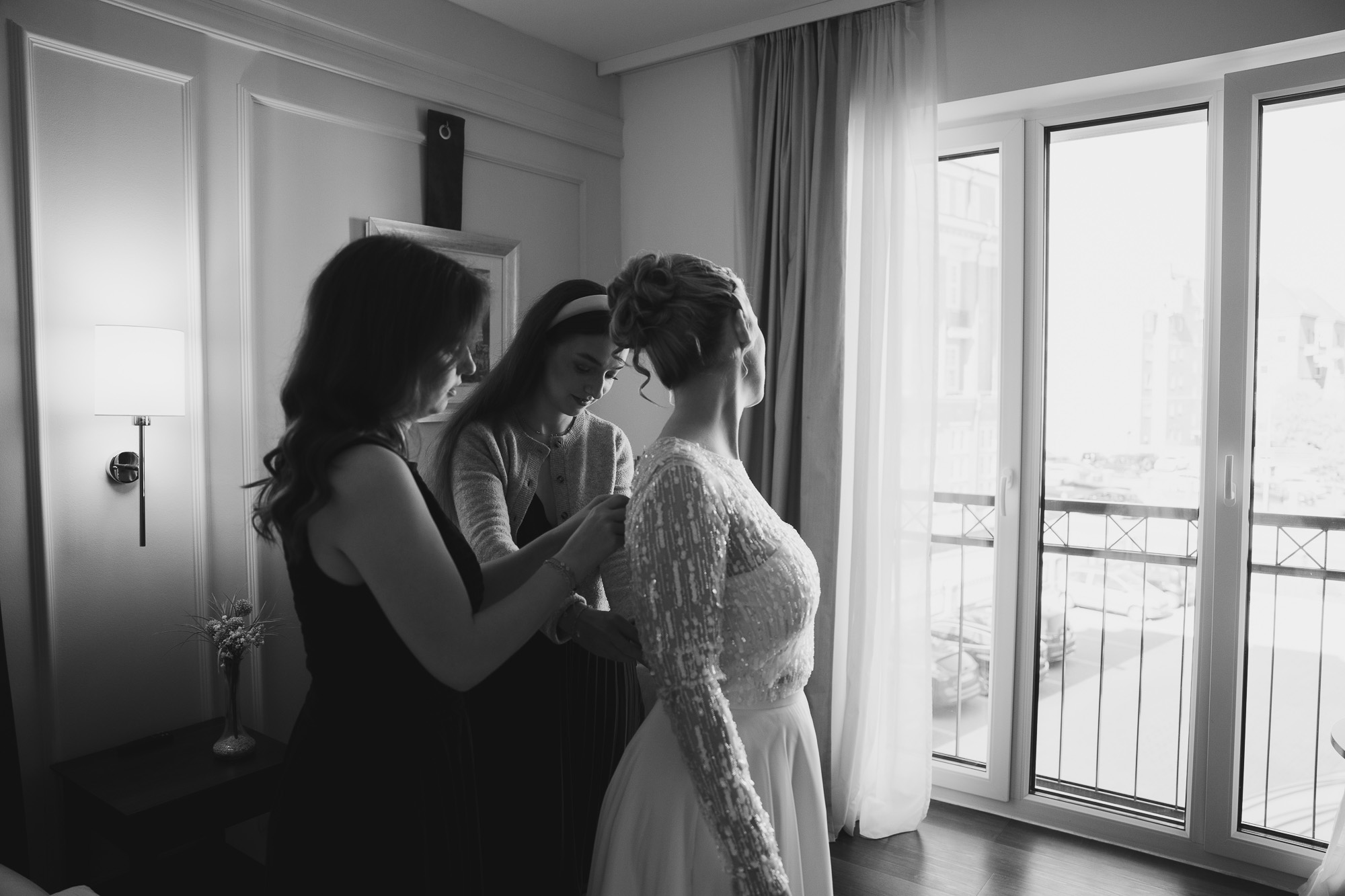 Black-and-white candid of women gathered together beside a bright window.