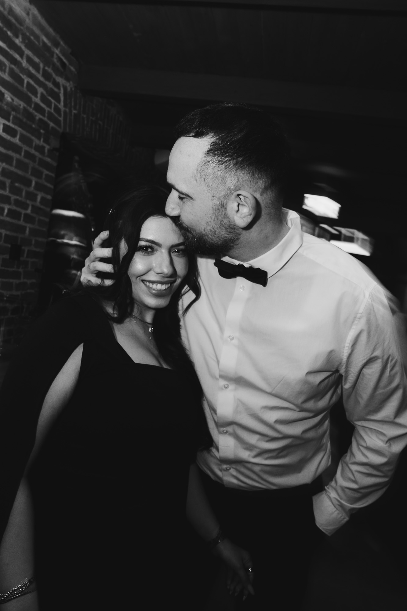 Black-and-white candid of wedding guests laughing together during the evening reception.