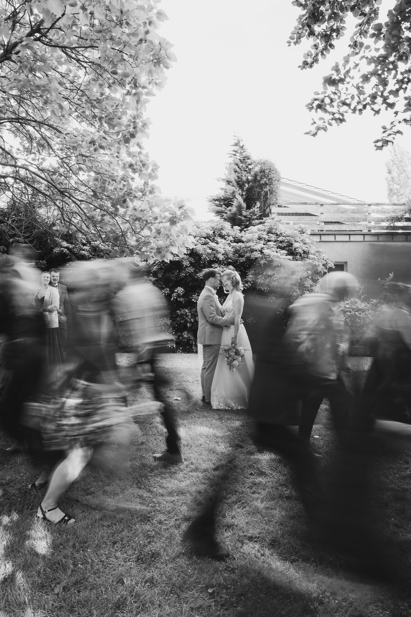Black-and-white photograph of wedding guests moving through the frame with expressive motion blur.