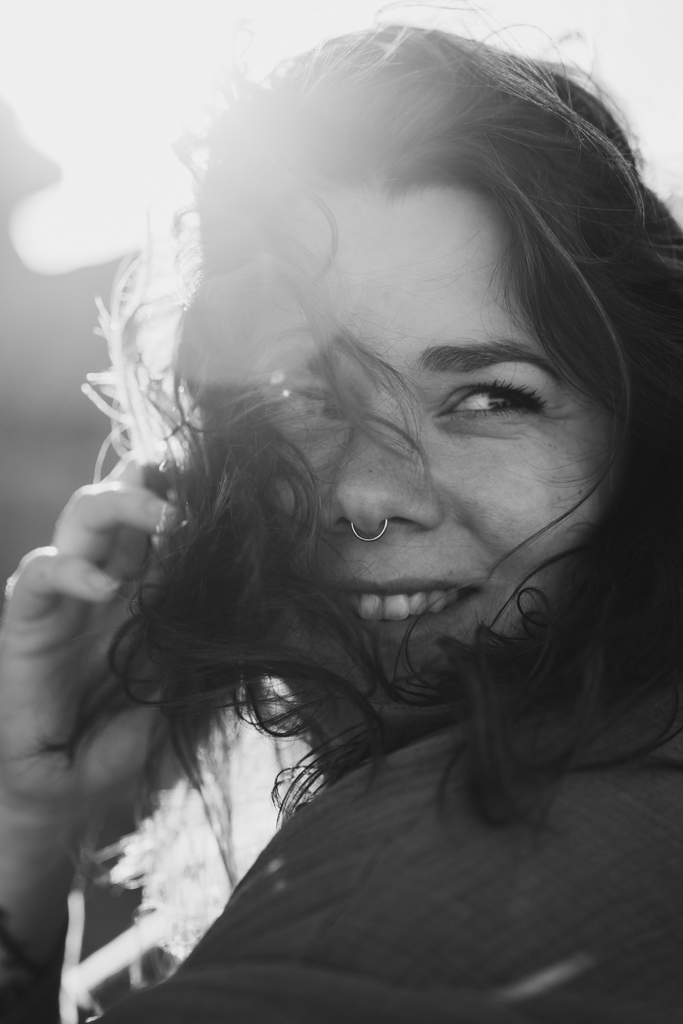 Black-and-white close-up portrait of a smiling woman with windblown hair.