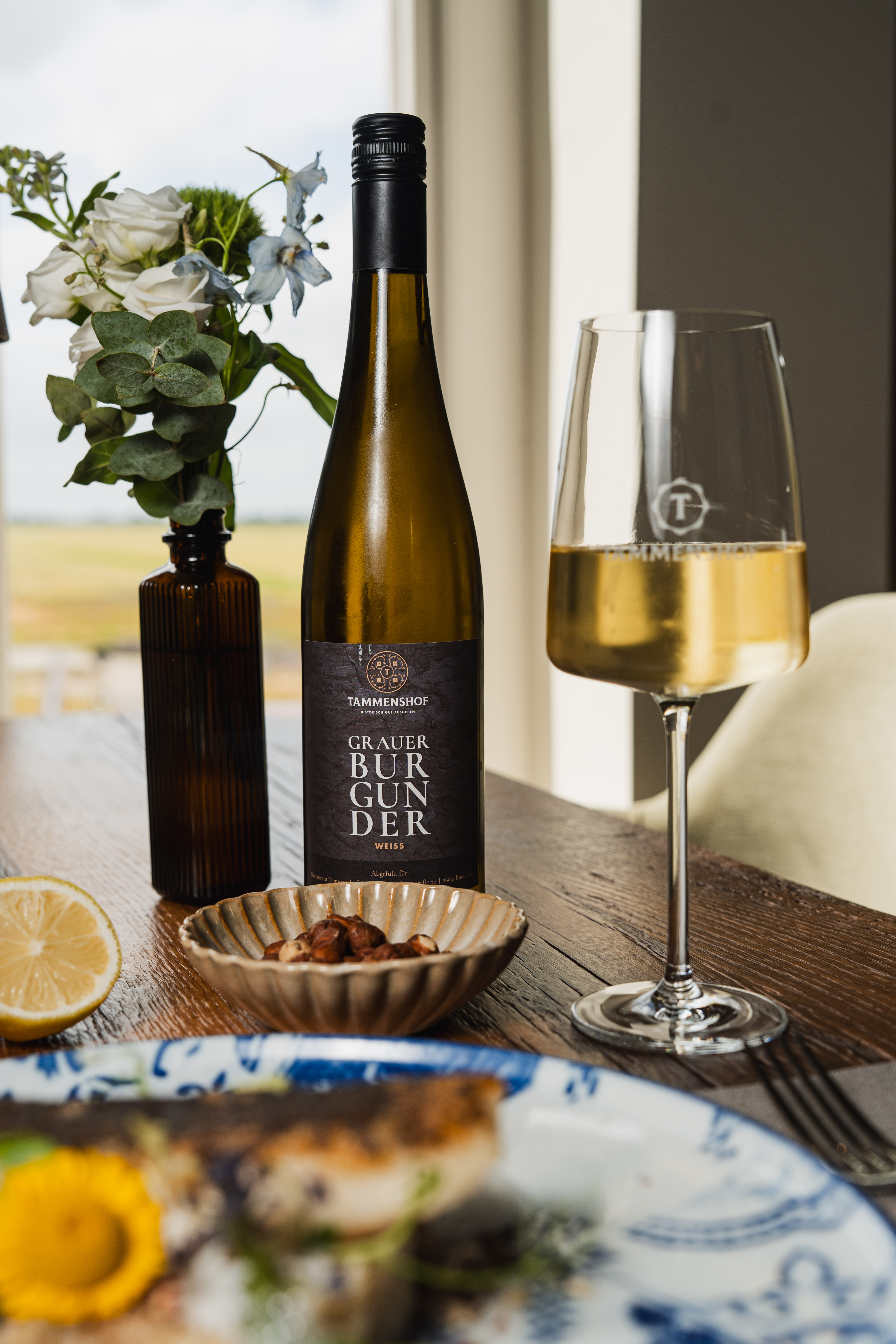 White wine beside a plated summer dish on a wooden table at Tammenshof.