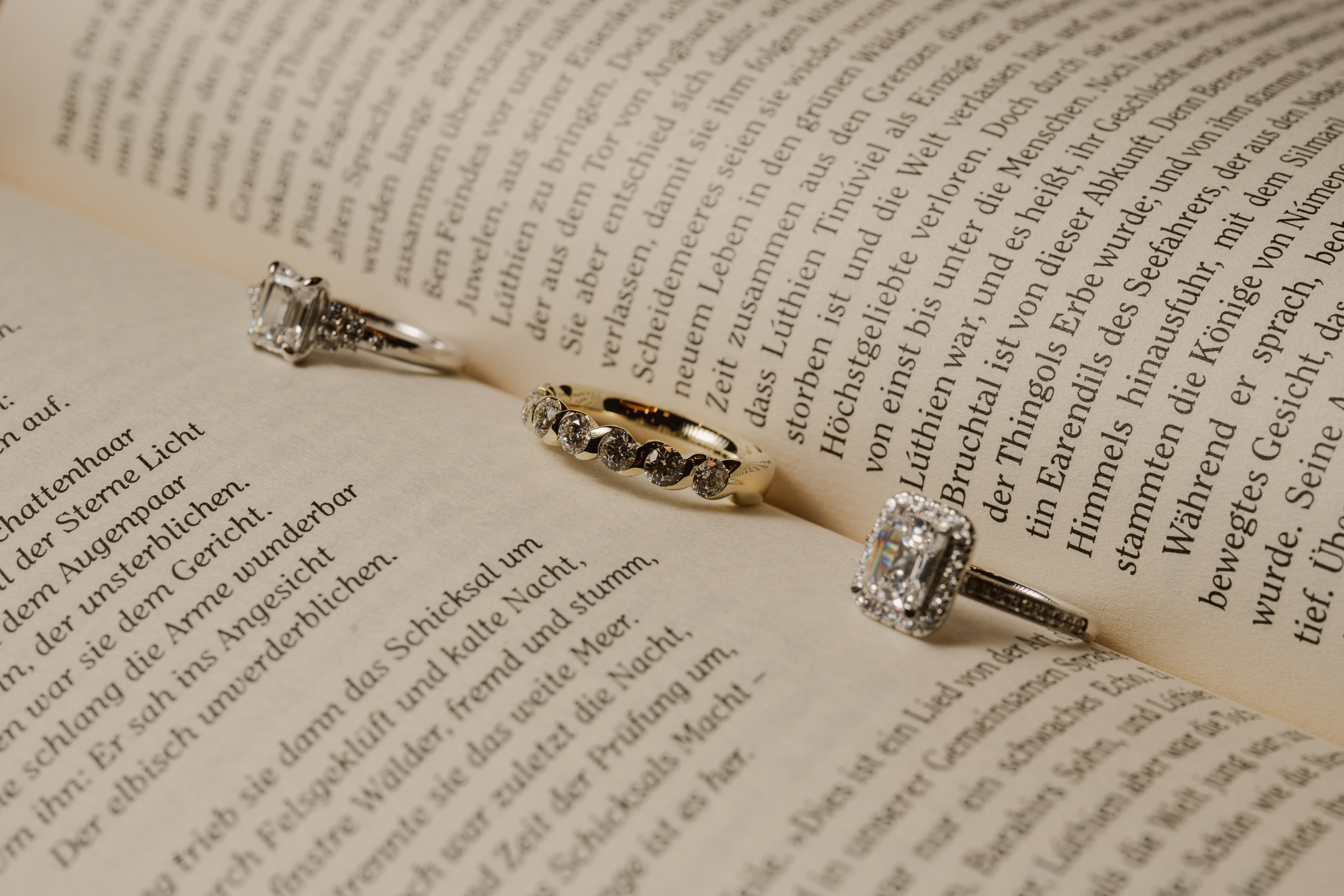 Three gemstone rings arranged across the open pages of a book.
