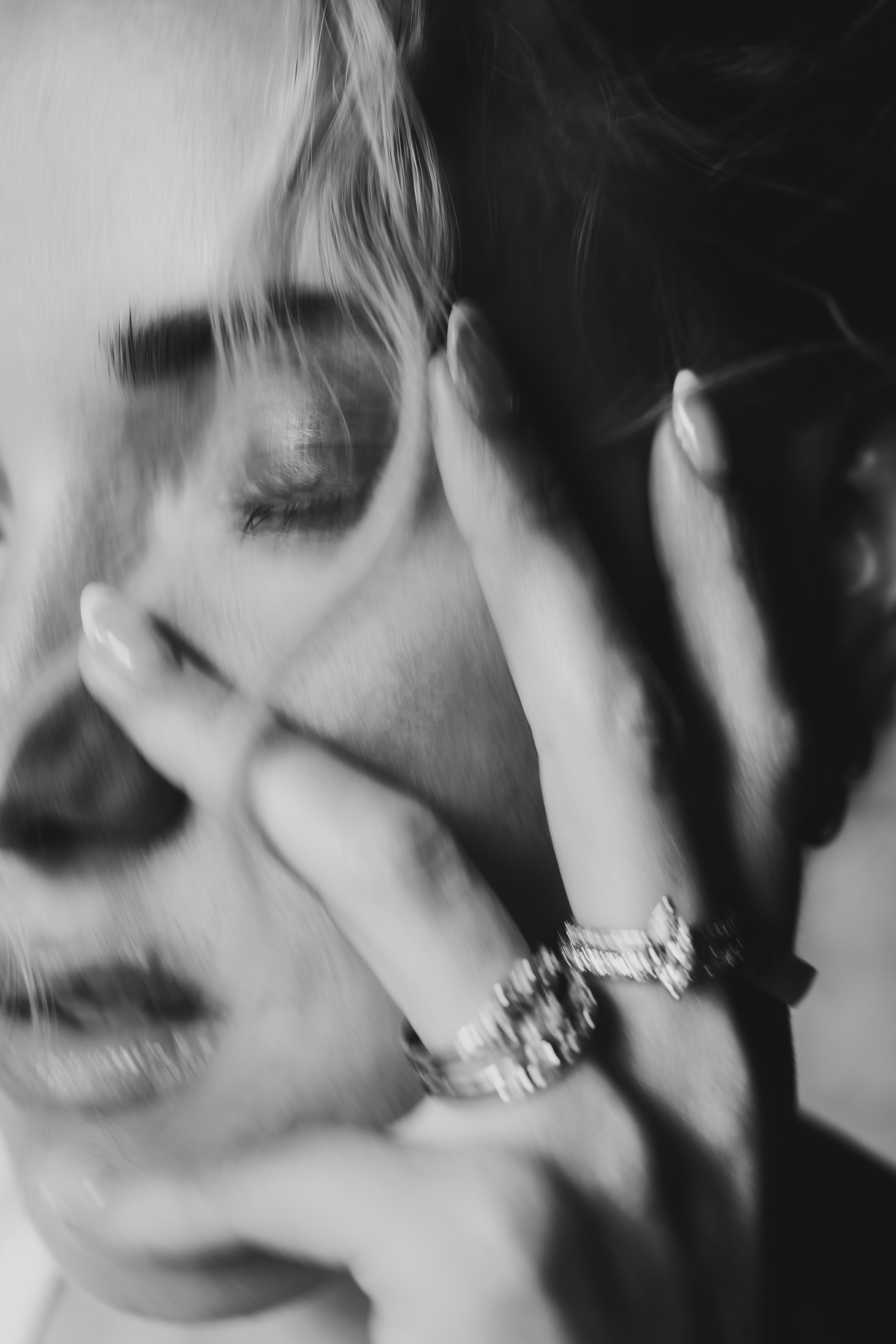 Black-and-white editorial portrait with rings catching the light across the woman’s face.
