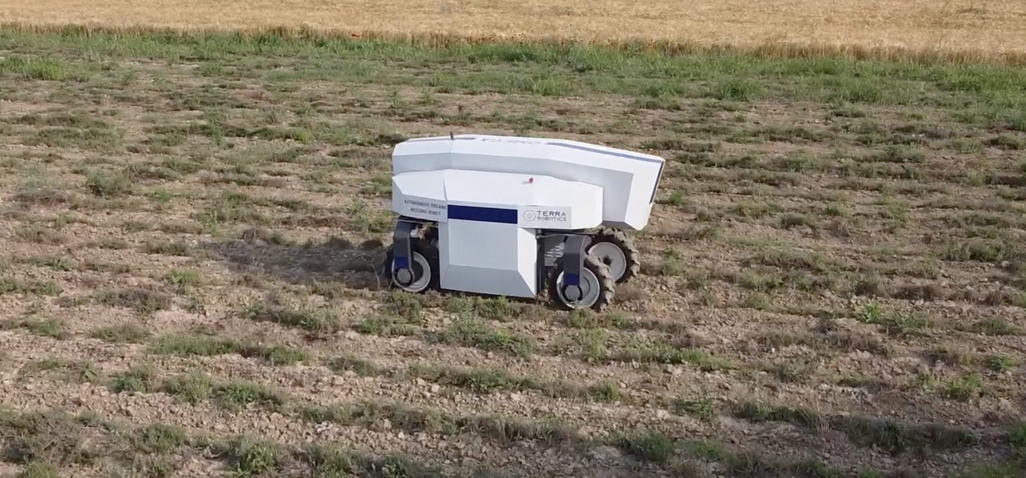 Autonomous agricultural robot with Terra Robotics branding working on a cultivated field.