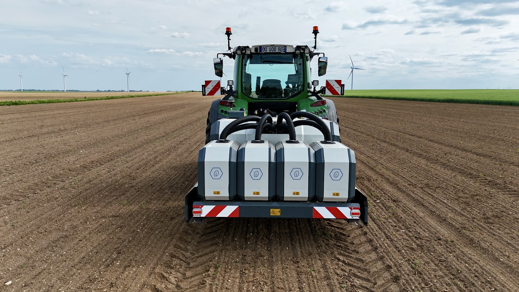 Rear view of tractor with Terra Robotics Weeder Core on large ploughed field under cloudy sky.