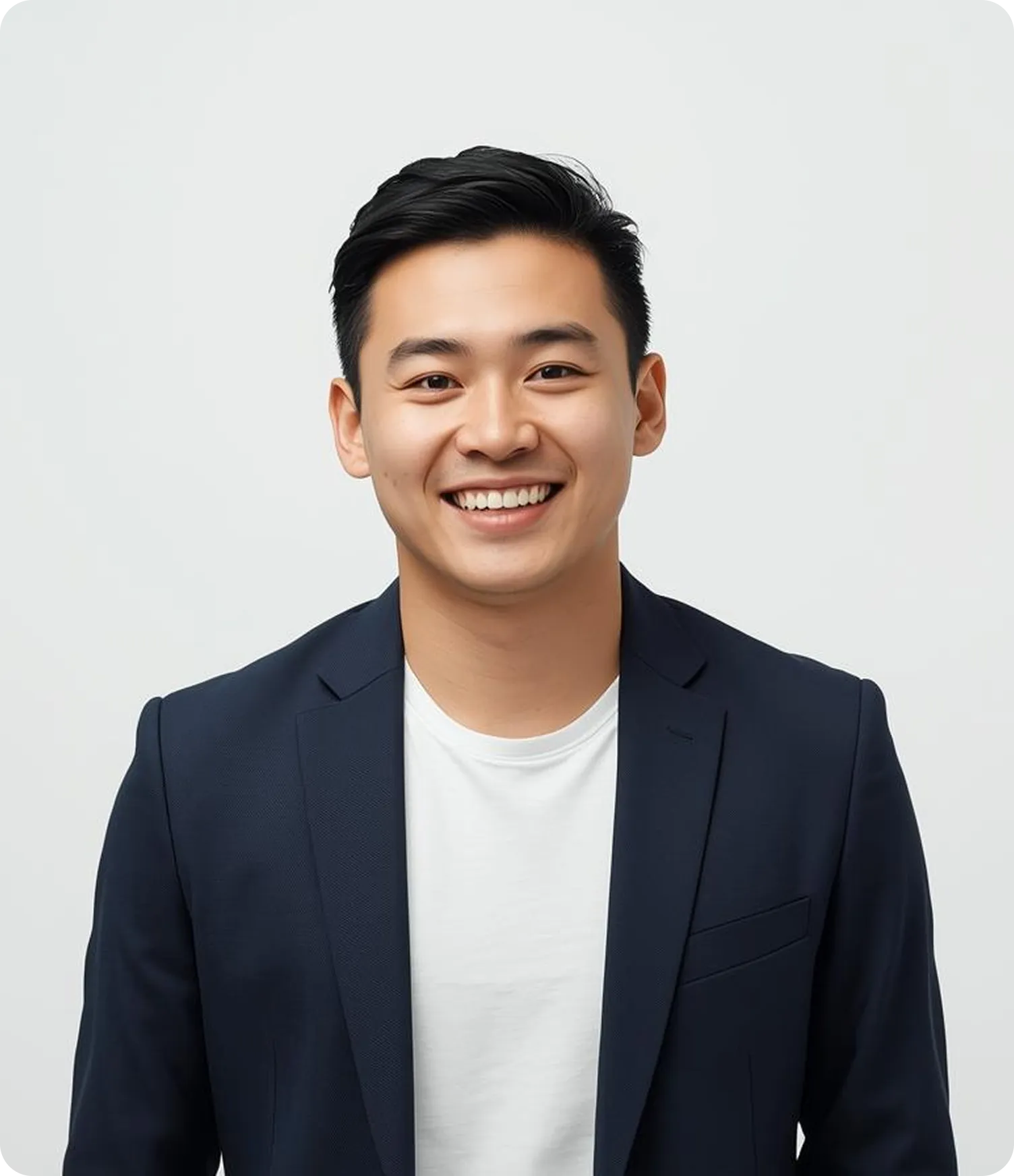Smiling young Asian man wearing a navy blazer and white t-shirt against a plain light background.
