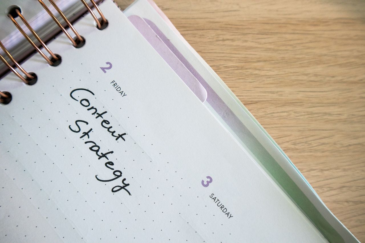 : Professionnel planifiant une stratégie de contenu avec un calendrier éditorial et des notes sur un bureau illustrant l'organisation d'une stratégie éditoriale web