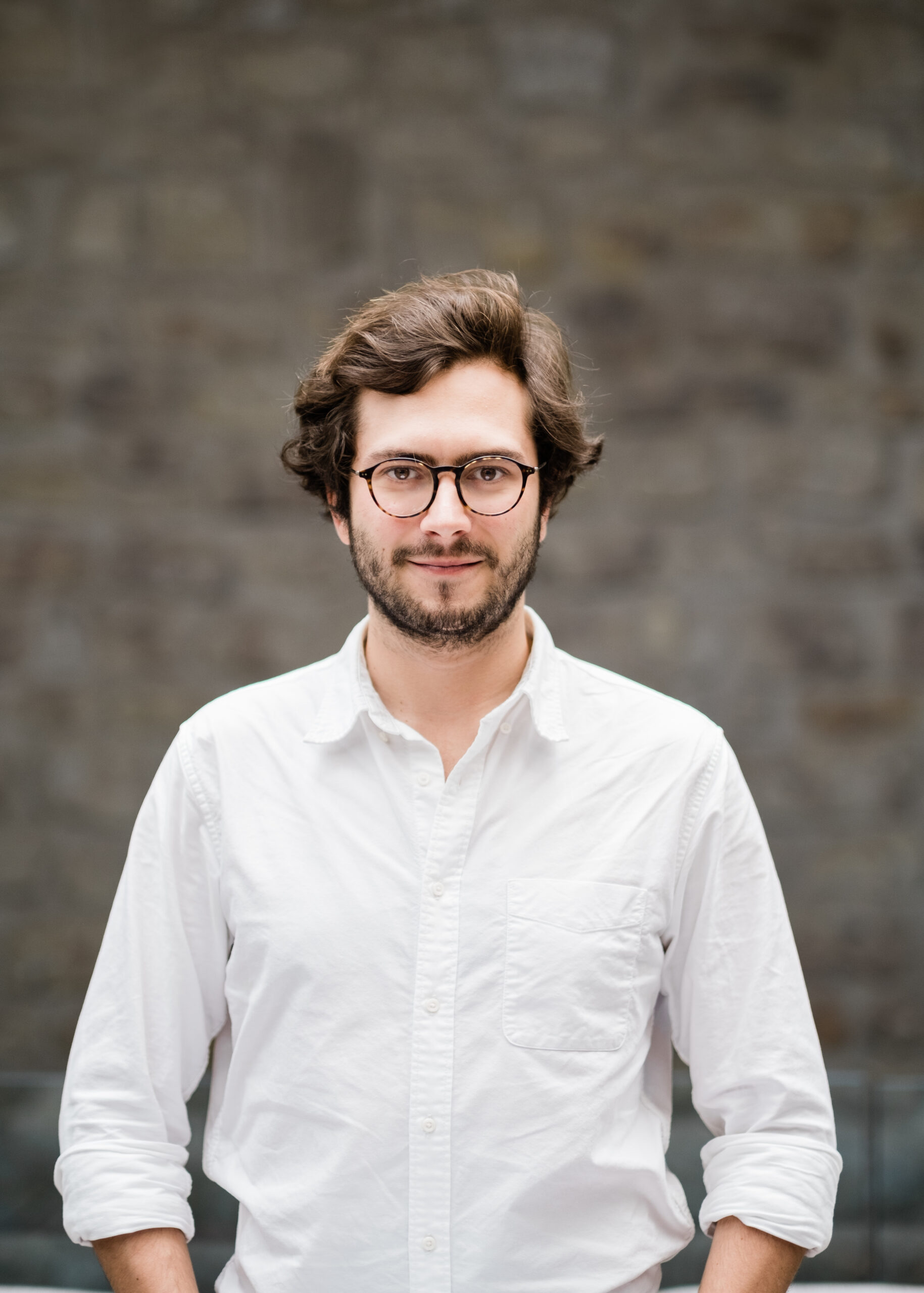 Portrait of a bearded Black man against a blue background with soft, diffused lighting.