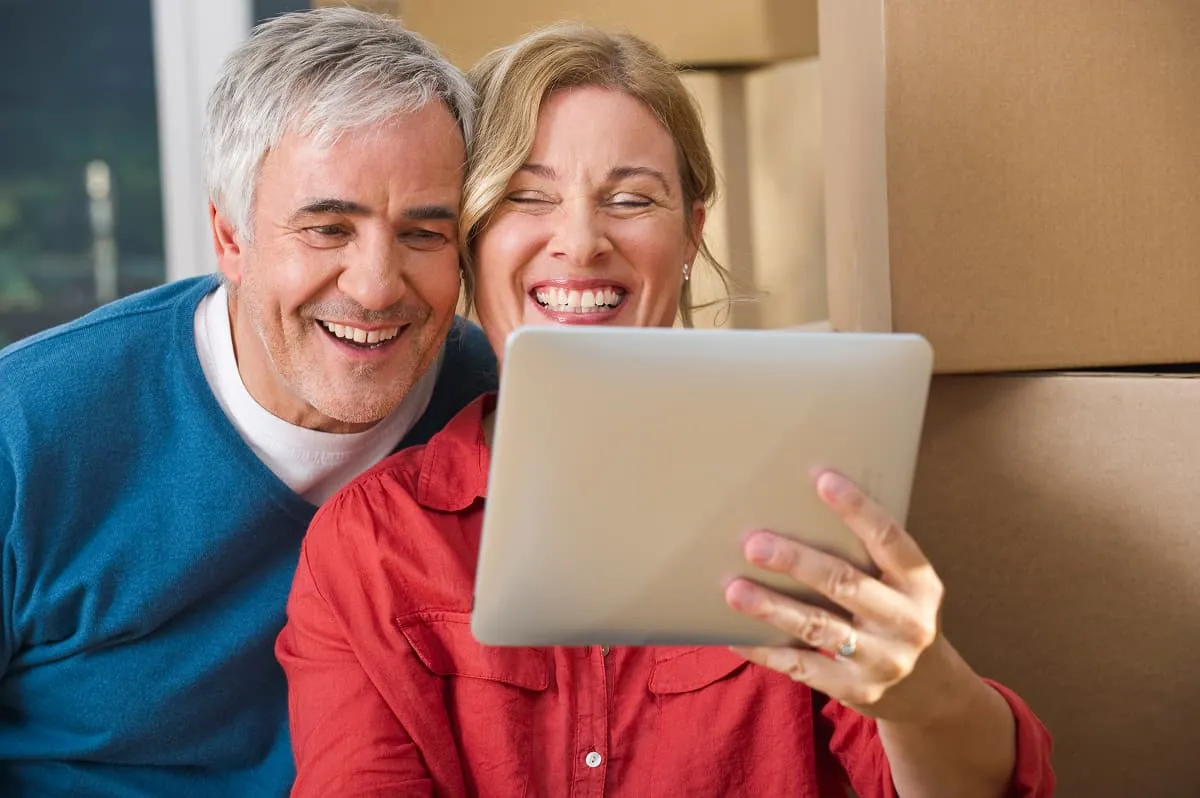 A couple smiling while looking at a tablet together
