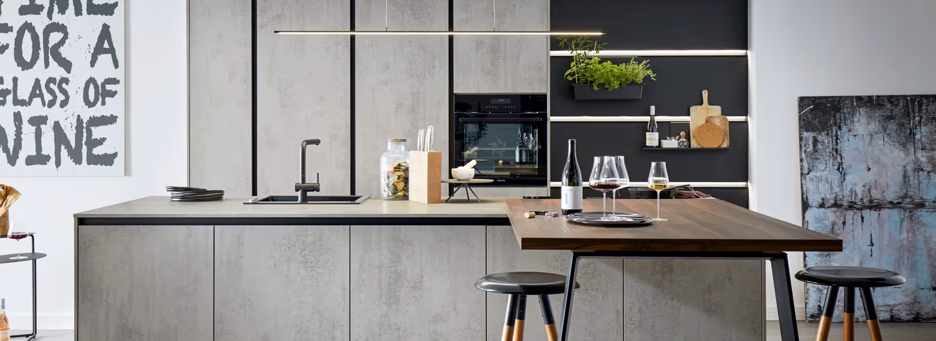 Modern minimalist kitchen with concrete-effect cabinets, black worktop, integrated oven, open shelving and wooden breakfast bar with stools