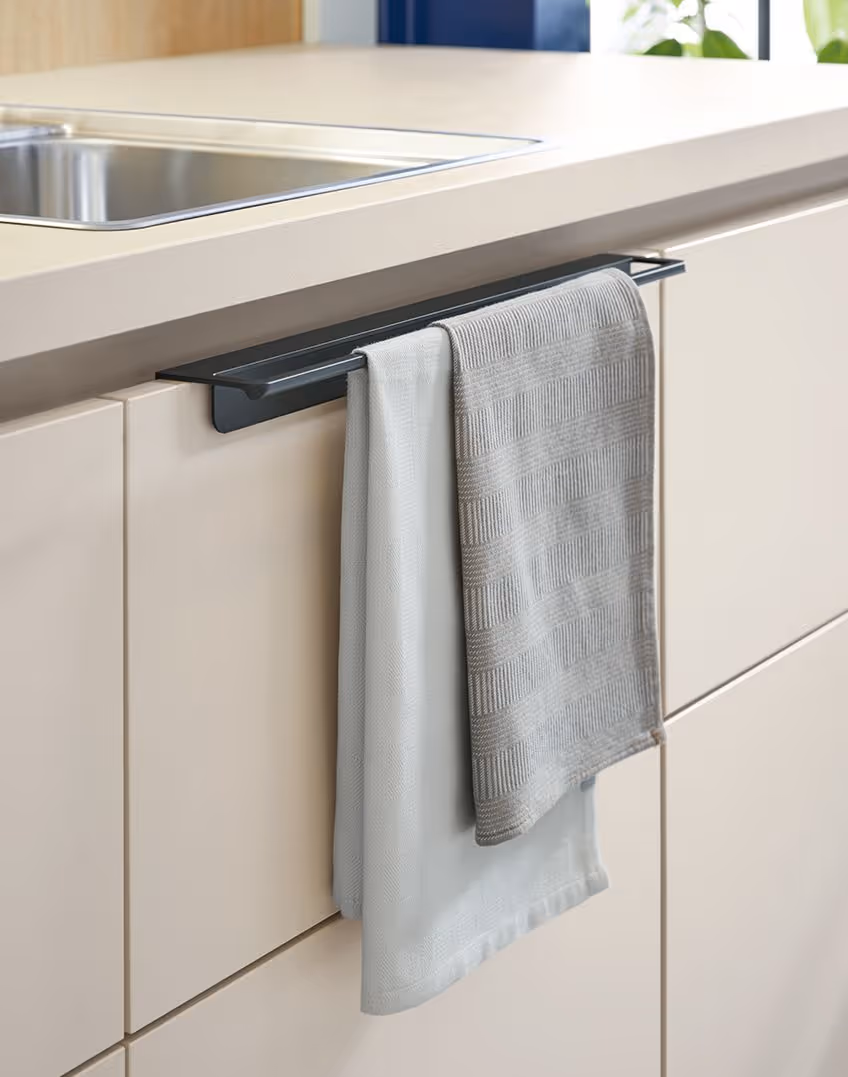 Two kitchen towels hanging on a handle under a sink.