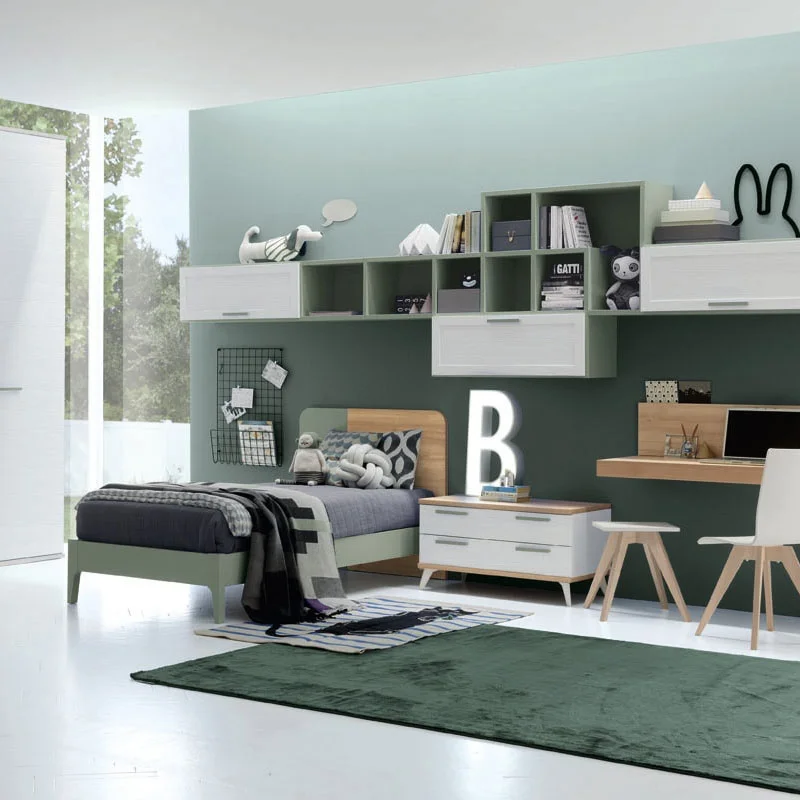 Modern bedroom with a bed, desk, and shelves. Decorative items and a green rug are visible.
