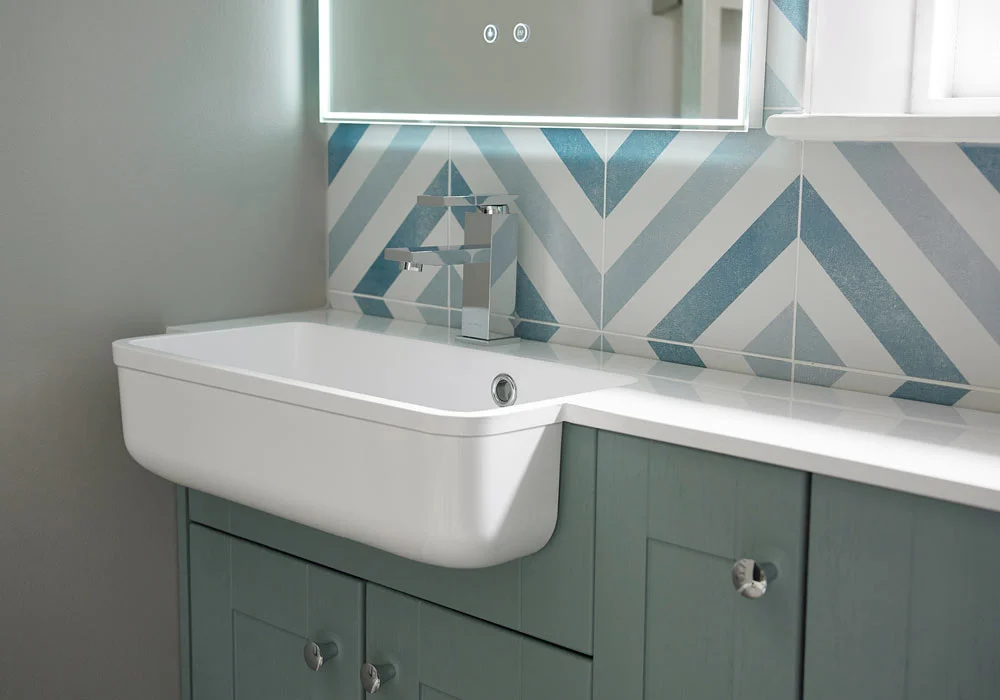 Bathroom sink with modern faucet and blue geometric-patterned tiles on the wall.