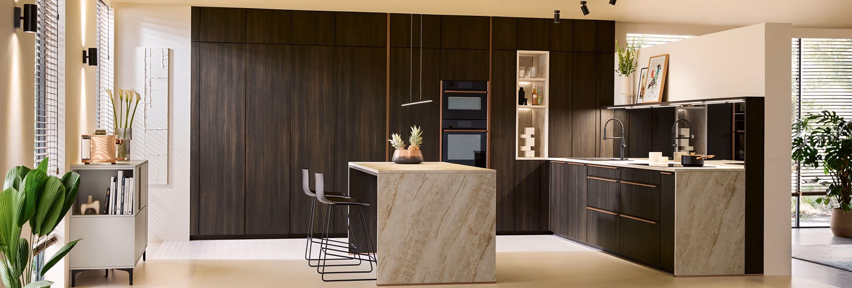 Modern kitchen with dark wood cabinets, marble island, and built-in appliances. Two stools are at the counter.