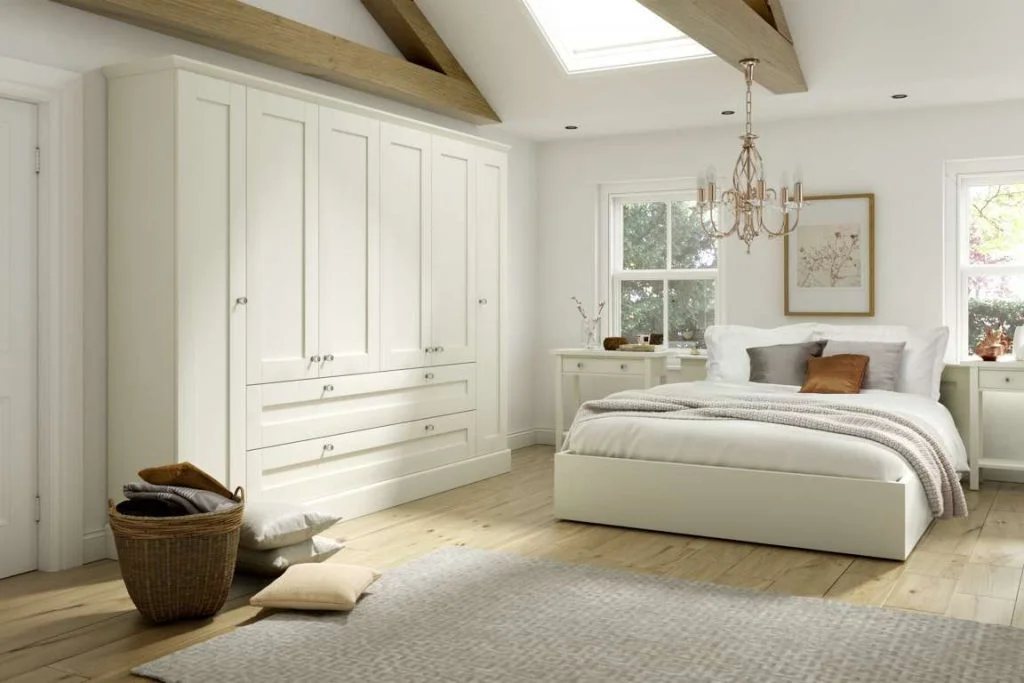 A bedroom with a bed, white wardrobe, and a ceiling light. A skylight adds natural light.