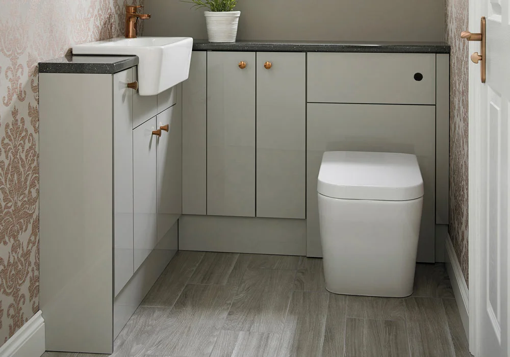 Modern bathroom with a white toilet, sink, and grey cabinets under a potted plant.