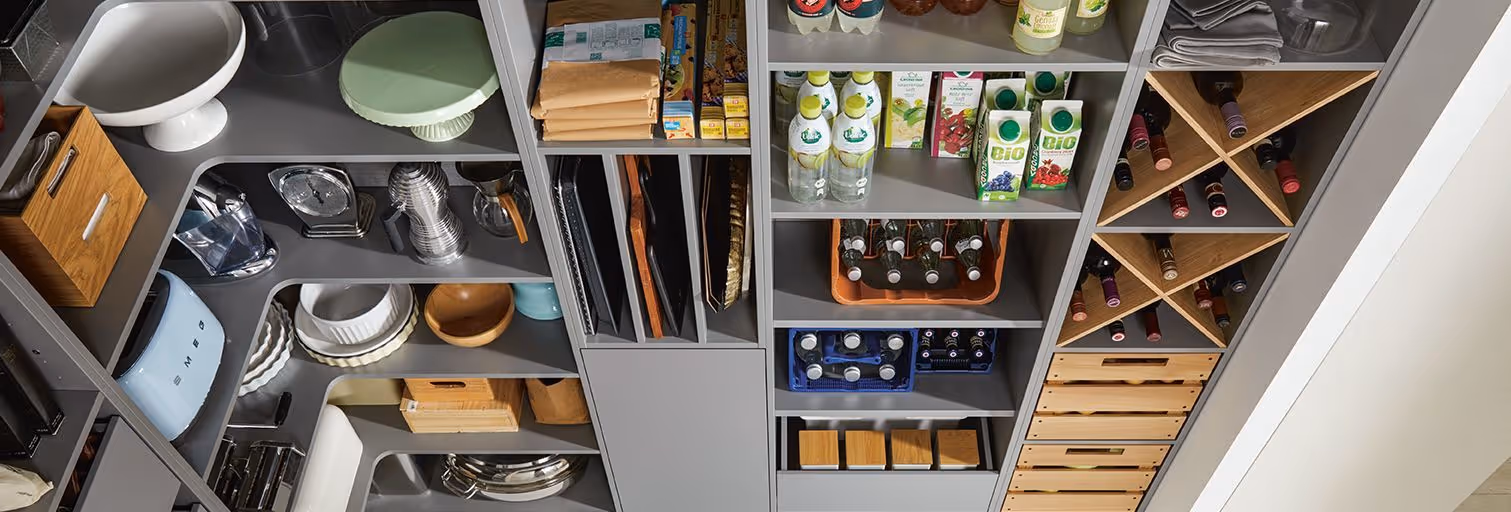A neatly organized pantry with shelves containing bottles, boxes, wine, and kitchen items.