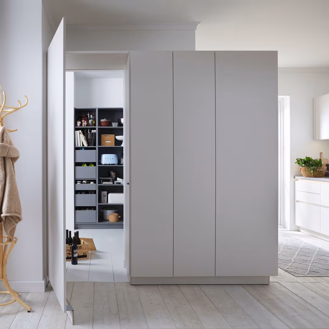 A pantry door is open, revealing organized shelves with food items and a kitchen area nearby.