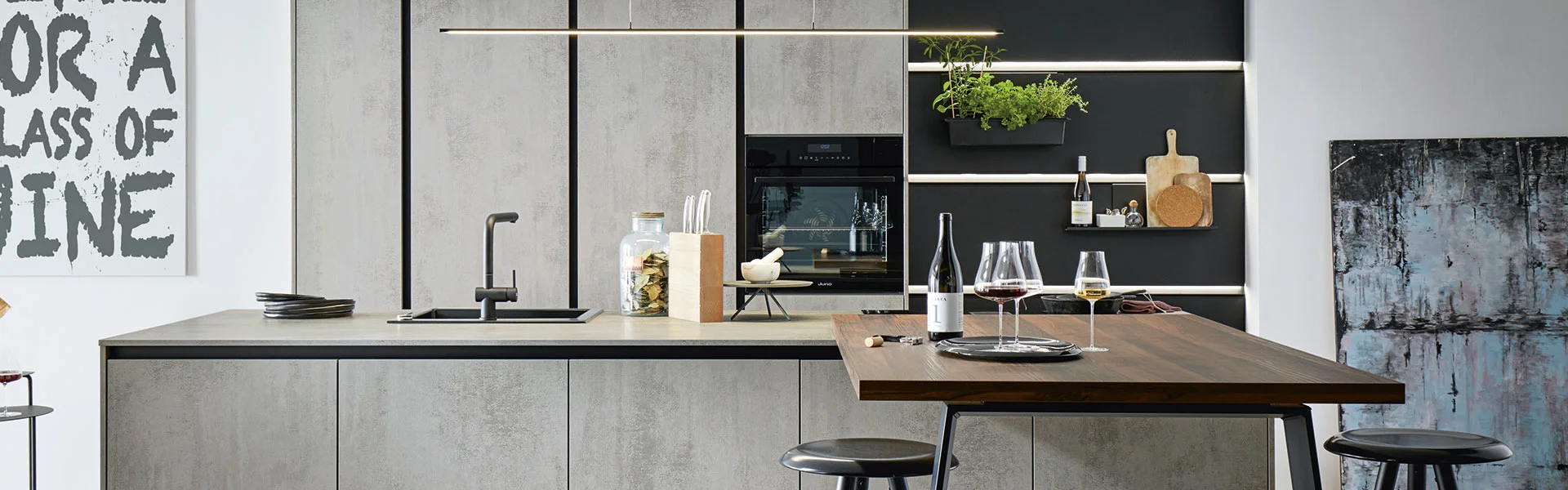 Modern kitchen with a wooden island, two bar stools, and glasses on the counter.
