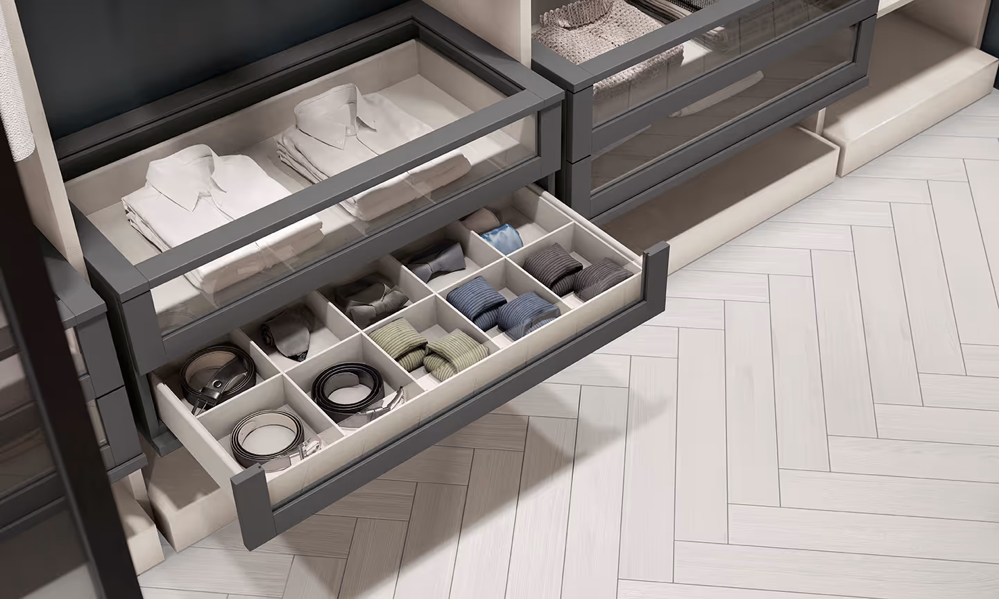 An open drawer with neatly organized shirts, ties, and belts inside a wardrobe.