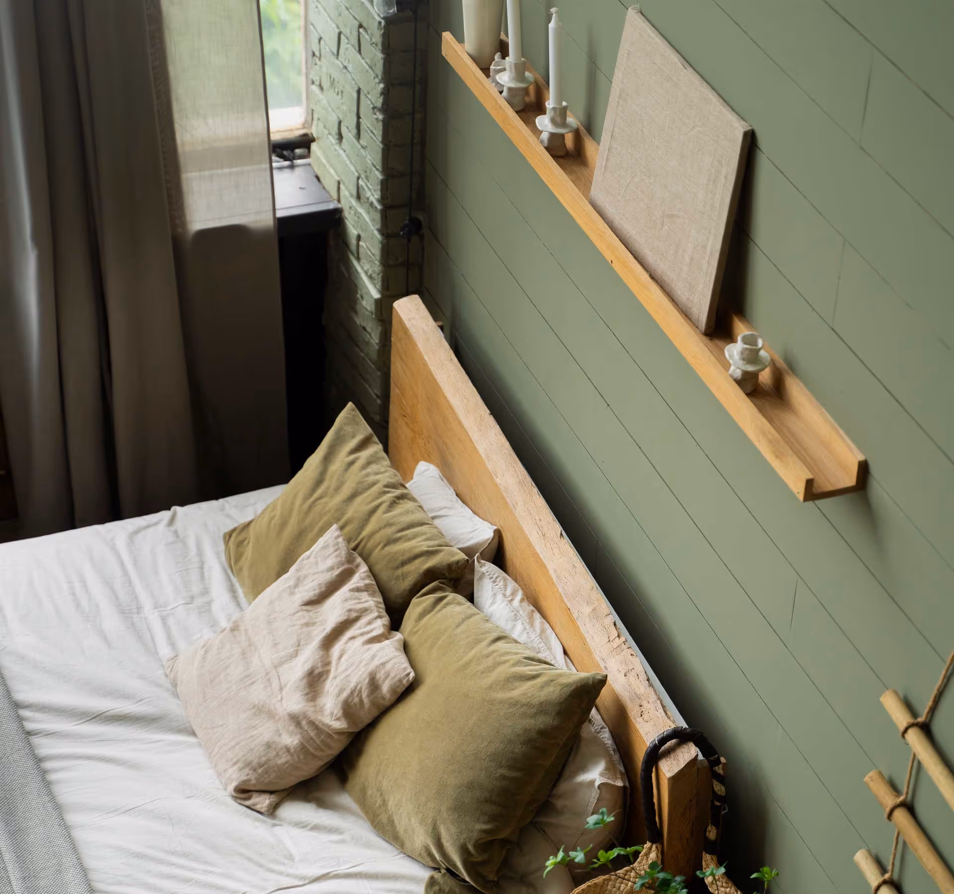 A neatly made bed with green pillows and a wooden headboard in a cozy bedroom.
