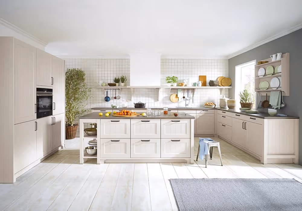 A modern kitchen with light wood cabinets, a central island, and various cooking items on shelves.