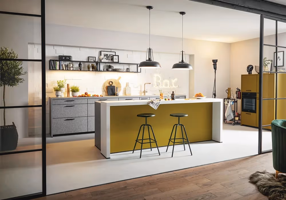 Modern kitchen with a yellow island, two stools, and hanging lights. Kitchenware and plants decorate shelves.