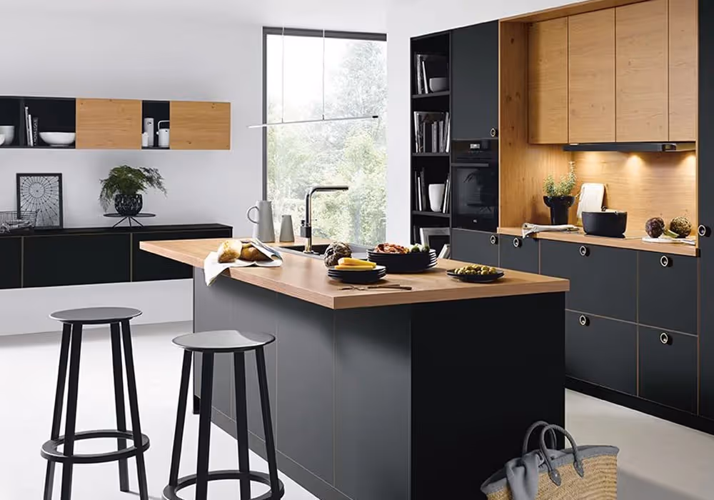Modern kitchen with black and wooden cabinets, a wooden island, and two stools in the foreground.