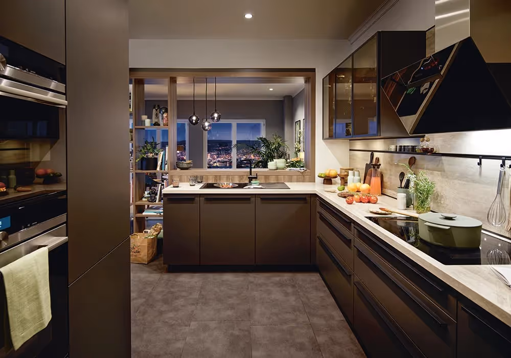 Modern kitchen with dark cabinets, a variety of cooking utensils, and fresh fruit on the counter.