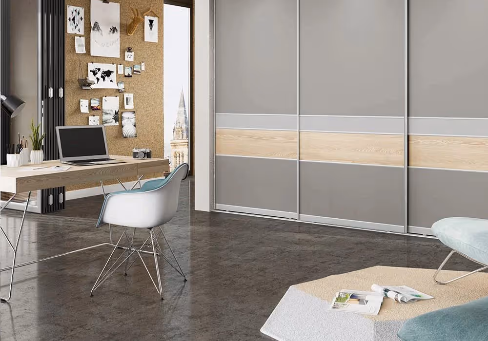 A modern office with a desk, laptop, chair, and a gray closet with sliding doors.