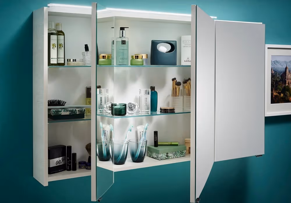 Open bathroom cabinet displaying various toiletries and grooming products on glass shelves.