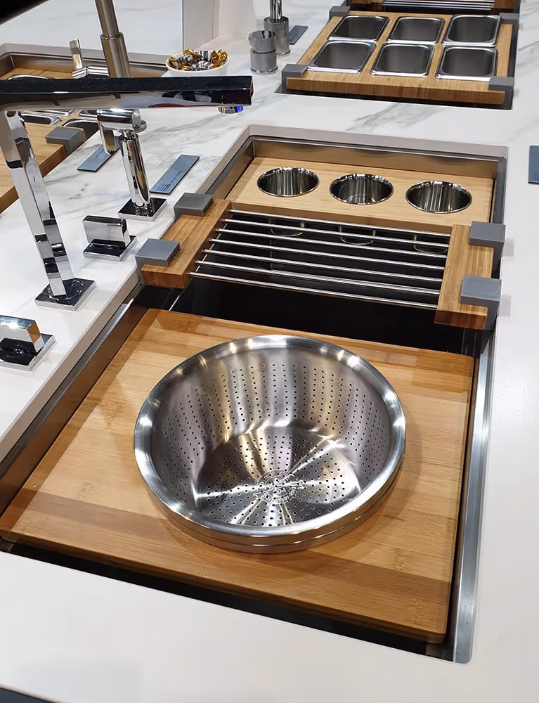 Modern kitchen sink with built-in wooden cutting board, metal colander, and adjustable faucets.
