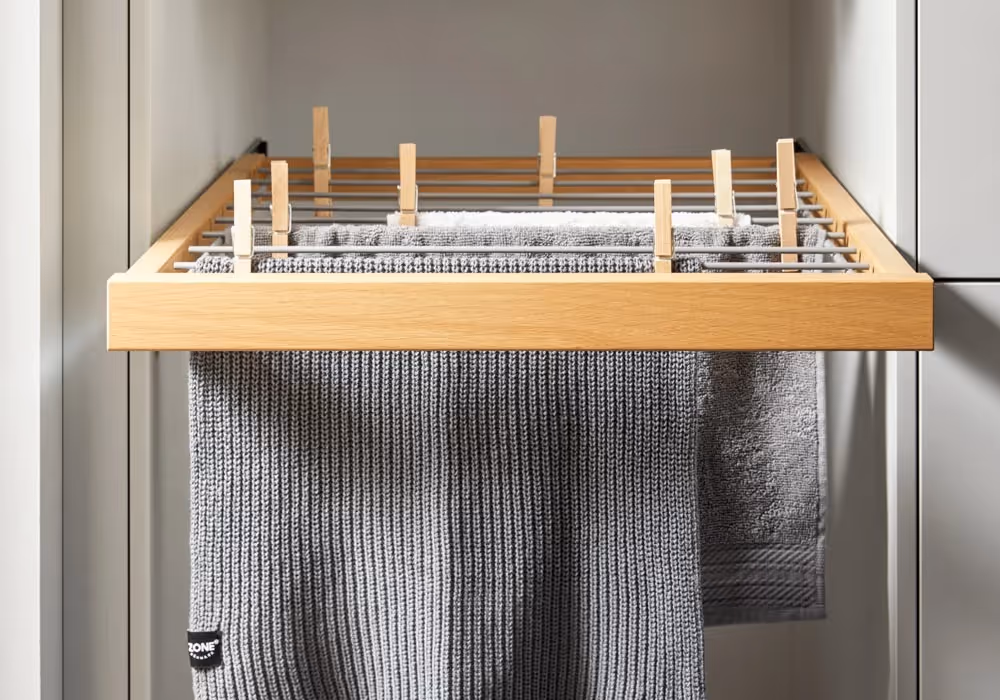 Wooden drying rack with multiple grey towels hanging neatly.