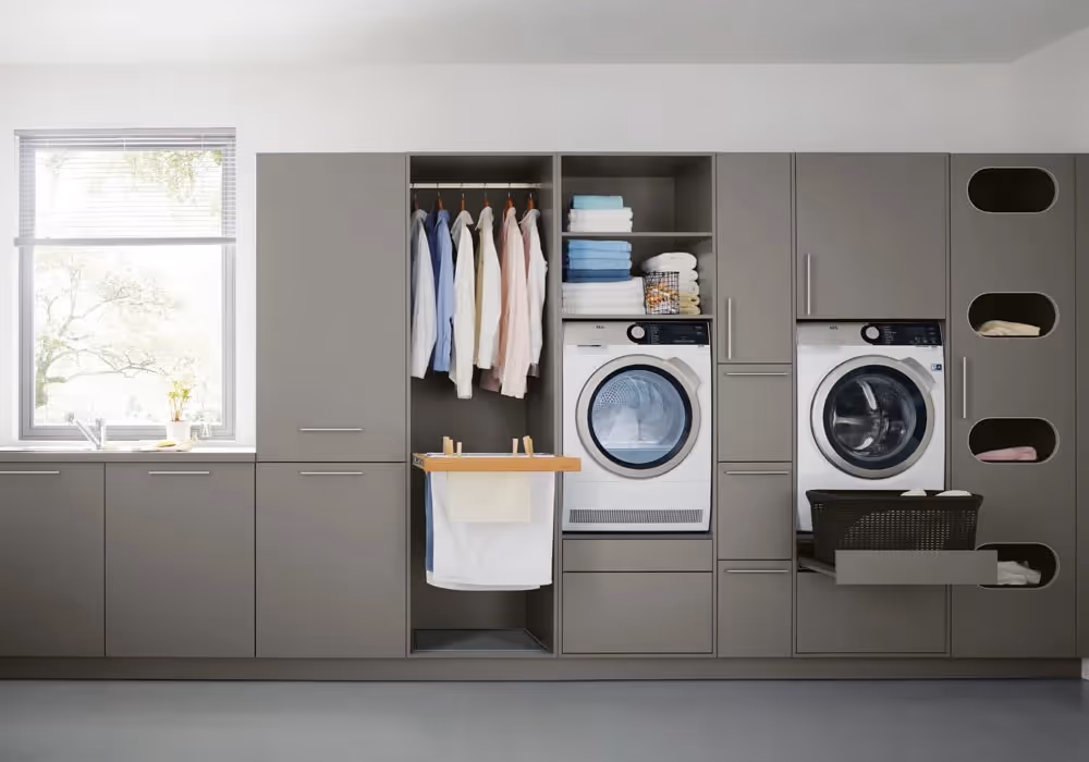 Laundry room with front-loading washer, dryer, and cabinets. Clothes hang in an open closet section.