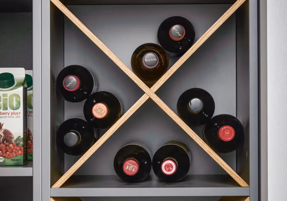 Wine bottles stored in a cross-shaped shelf next to a box of organic cranberry juice.