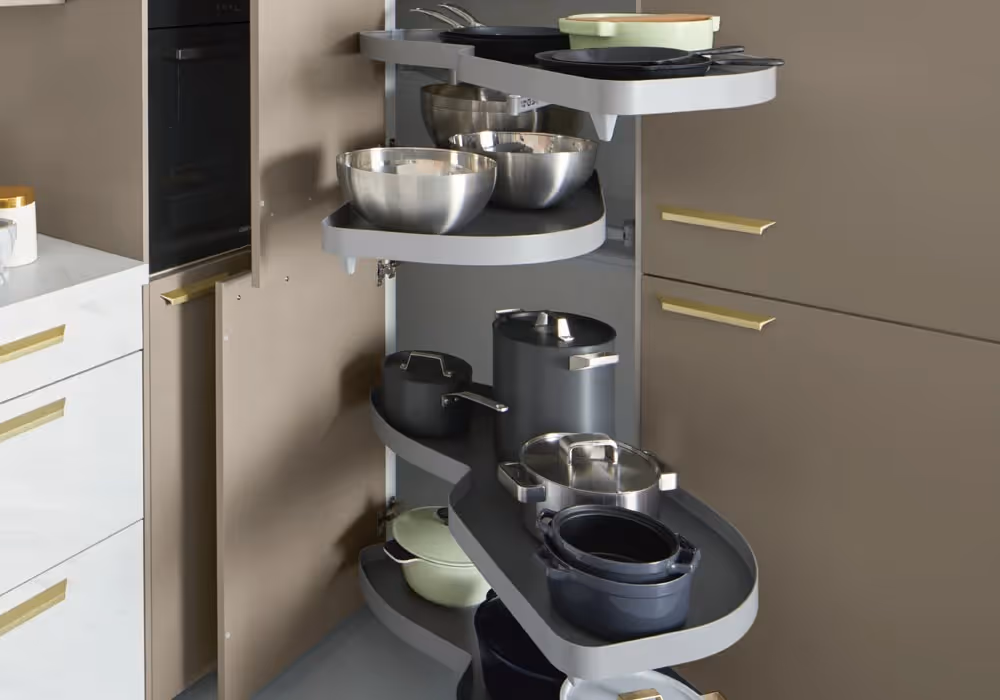 Pull-out kitchen cabinet with rotating shelves holding pots, pans, and bowls in a modern kitchen.