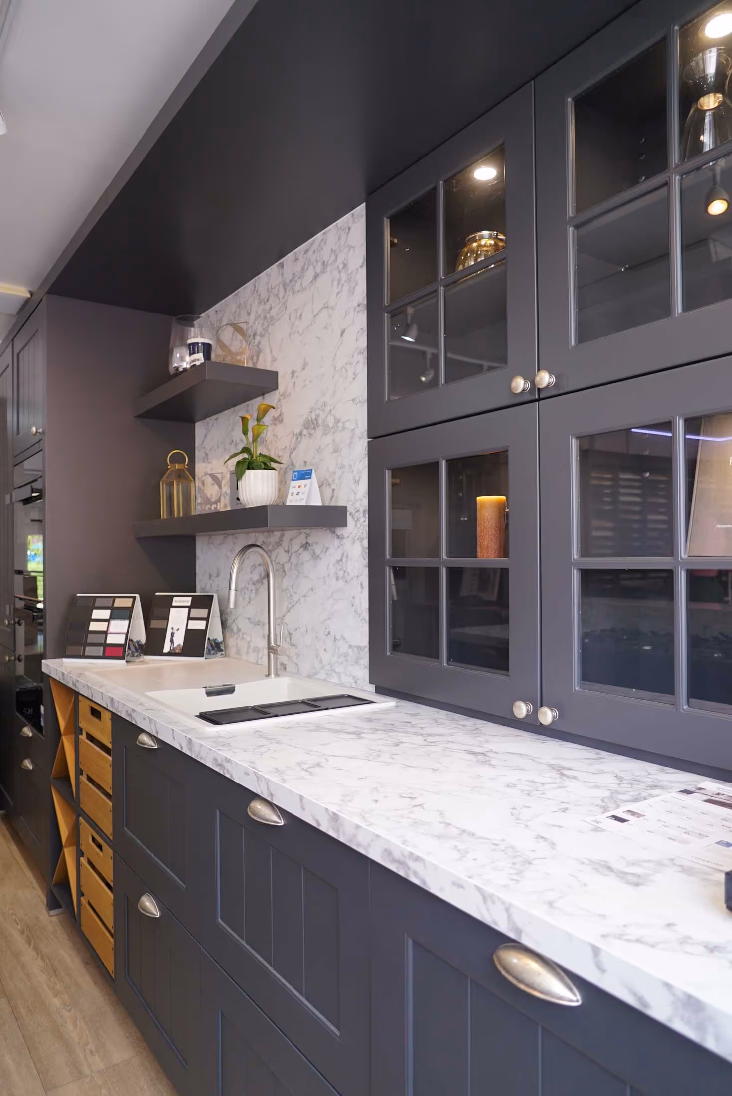 Modern kitchen with dark cabinets, marble countertop, and a sink with a faucet.