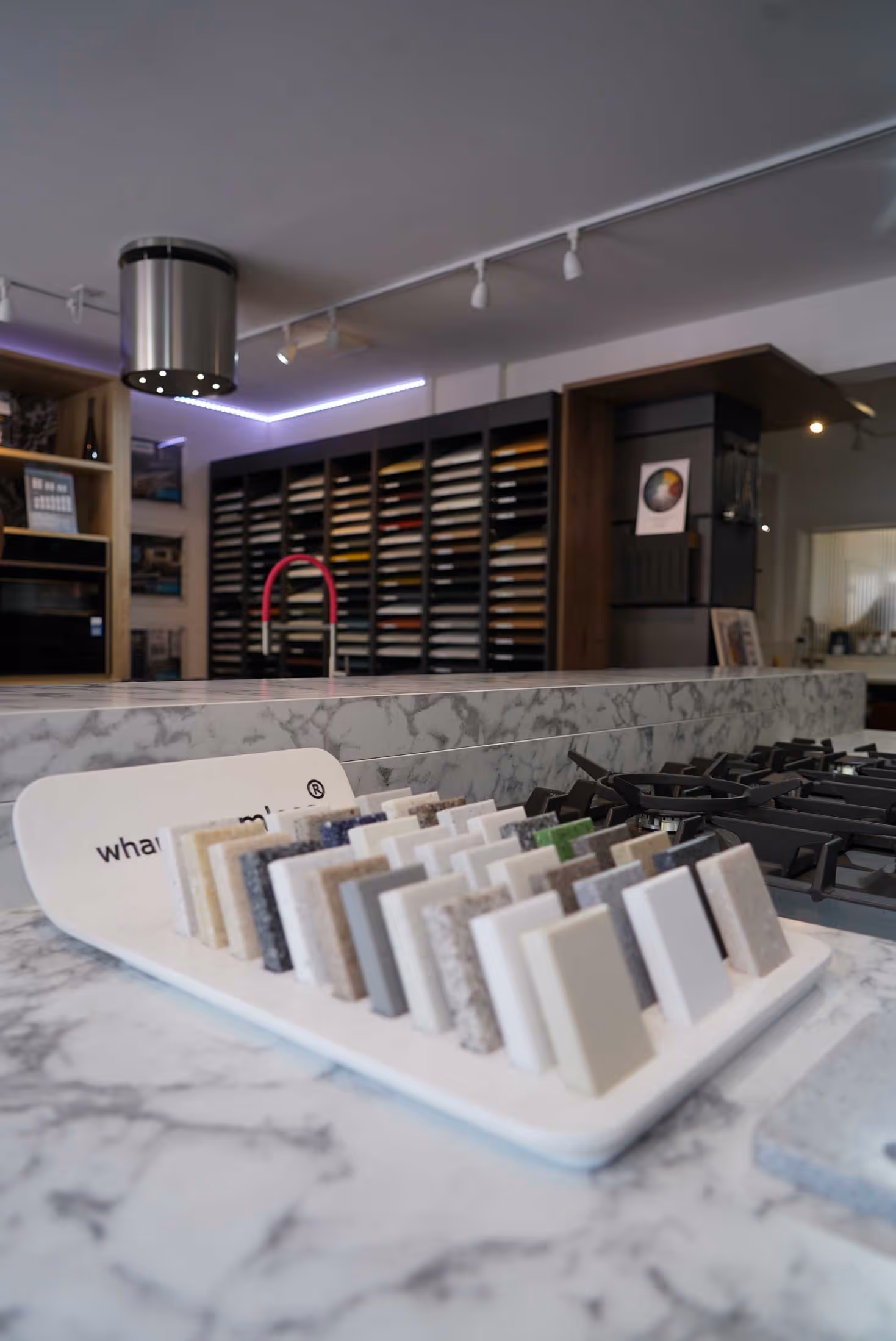 A display of countertop samples sits on a marble kitchen countertop in a showroom.