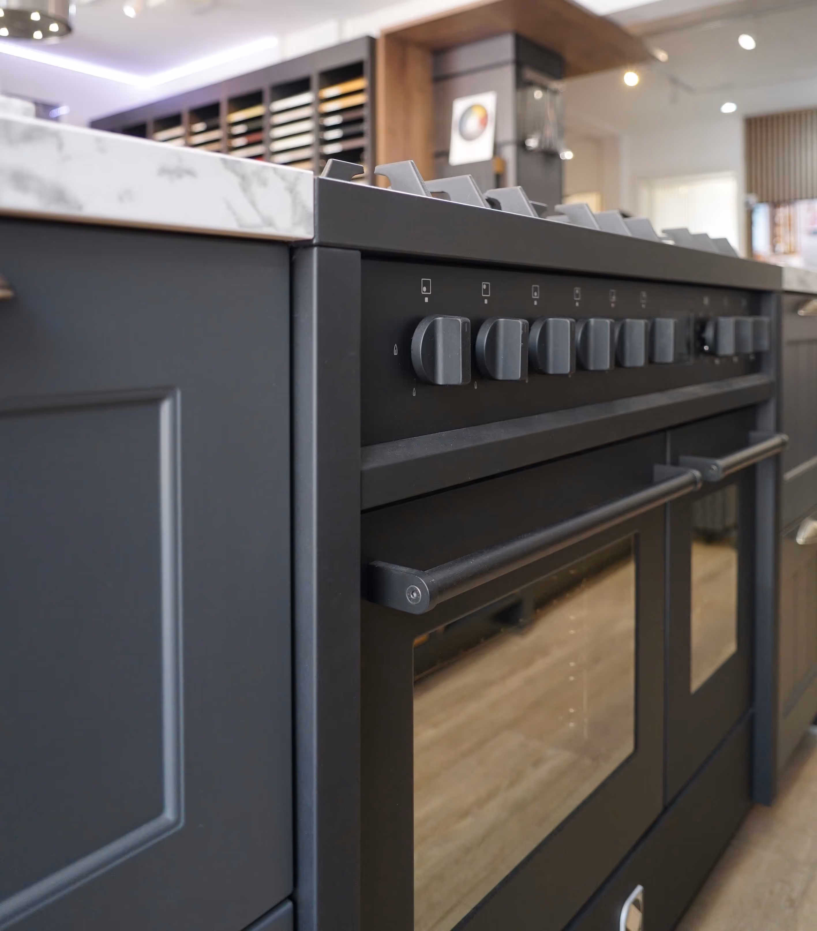 Close-up of a modern black kitchen stove with multiple knobs and a marble countertop.