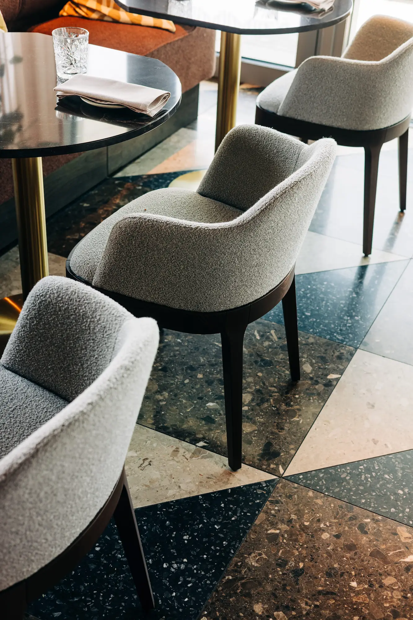 Fåtöljer vid dukade bord på terrazzogolv, interiör från Willow Hotel i Trelleborg