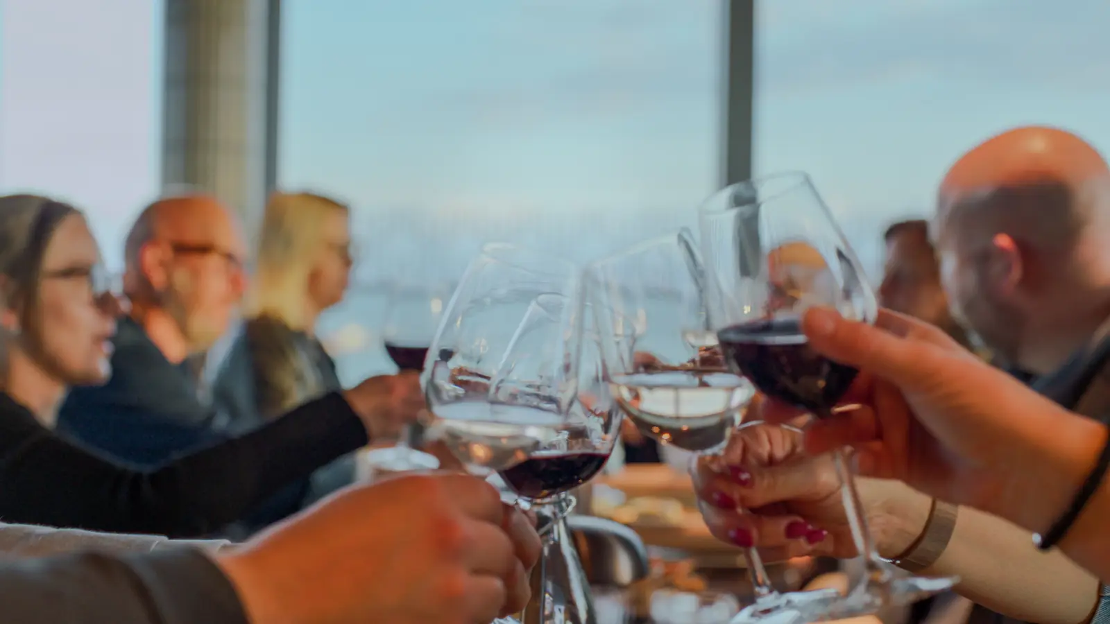 Gäster skålar med rött och vitt vin vid middagsbordet på Willow Hotel