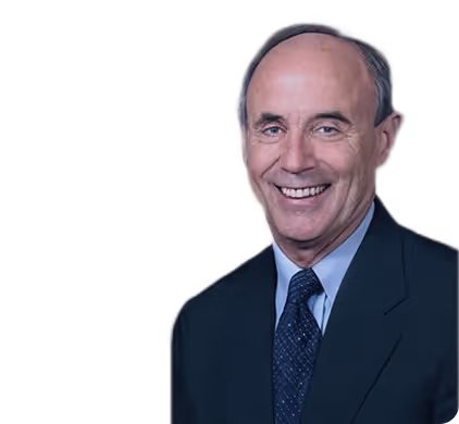 Smiling middle-aged man in a dark suit, blue shirt, and patterned tie with a bald head and gray hair on the sides.
