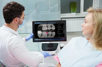 Dentist wearing mask and gloves showing a dental X-ray image to a female patient in the clinic.