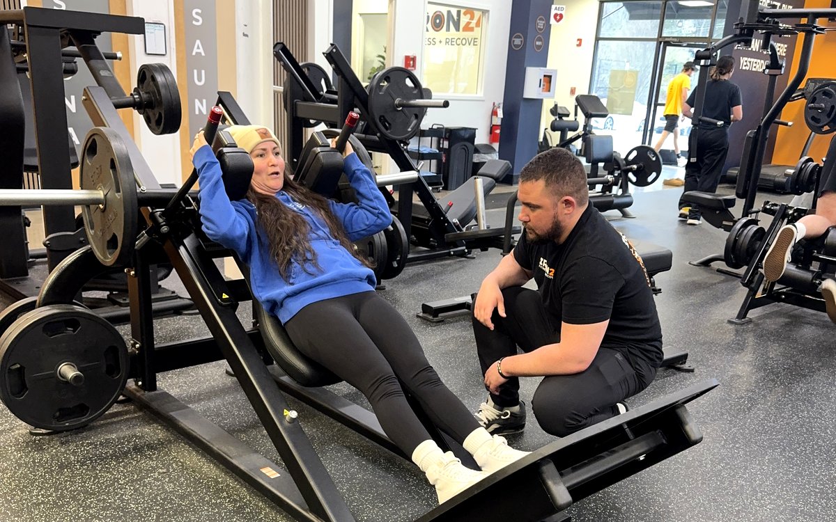 Coach spotting client on leg press at Iron 24