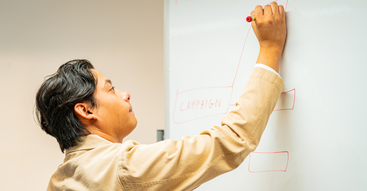 Medewerker tekent een procesdiagram op een whiteboard als beeld voor data als fundament van een succesvolle ESG-strategie.